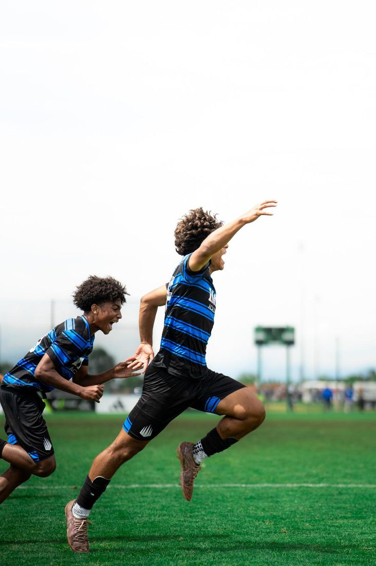 A young player sprinting away in celebration after scoring